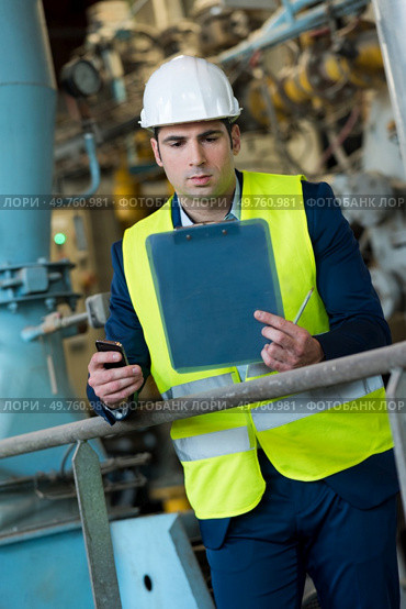 suited man in site holding clipboard and smartphone. Стоковое фото, агентство Ingram Publishing / Фотобанк Лори