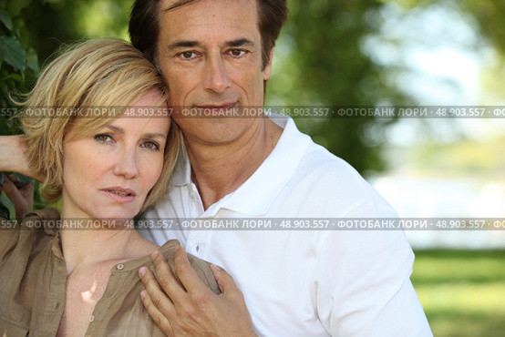 Sultry couple stood by tree in park. Стоковое фото, агентство Ingram Publishing / Фотобанк Лори