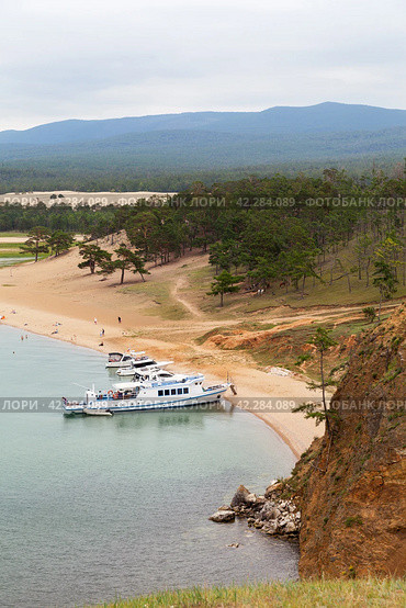 Summer holidays on Baikal Lake. Pleasure yachts, fishing ships and boats moor at Olkhon Island on sandy beach of Saraiskiy Bay. View from above from Cape Burkhan. Summer travel, fishing and rest. Стоковое фото, фотограф Виктория Катьянова / Фотобанк Лори