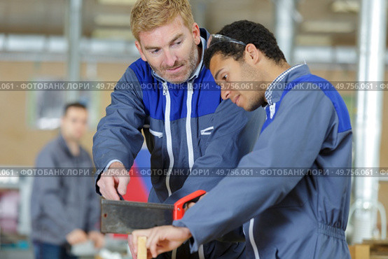 supervisor watching young trainee use a hand saw. Стоковое фото, агентство Ingram Publishing / Фотобанк Лори