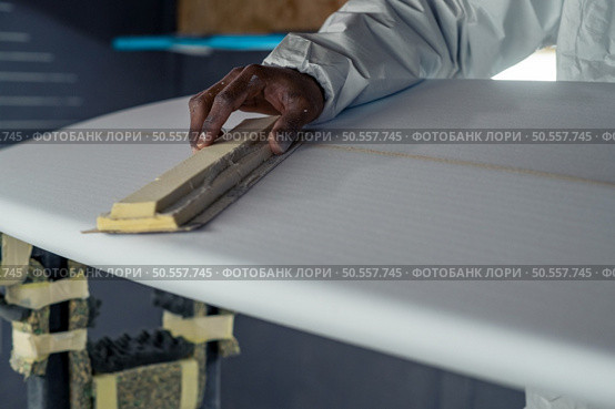 Surfboard manufacturing, Shaper working on board details. Concept of industrial manufacturing, qualified professional, occupation and employment. Стоковое фото, агентство Ingram Publishing / Фотобанк Лори