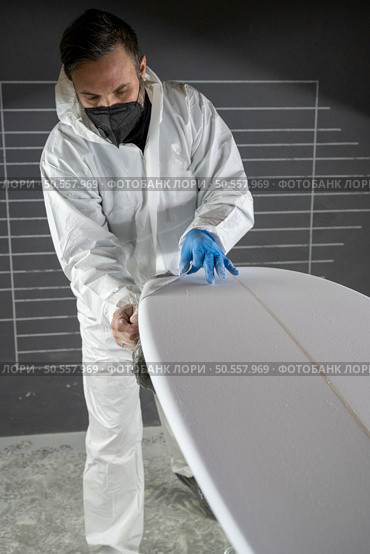 Surfboard manufacturing, Shaper working on board details. Concept of industrial manufacturing, qualified professional, occupation and employment. Стоковое фото, агентство Ingram Publishing / Фотобанк Лори