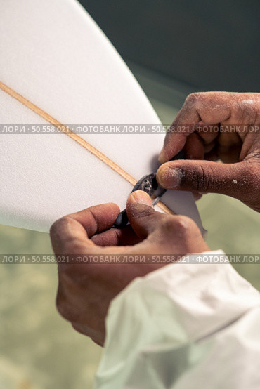 Surfboard manufacturing, Shaper working on board details. Concept of industrial manufacturing, qualified professional, occupation and employment. Стоковое фото, агентство Ingram Publishing / Фотобанк Лори