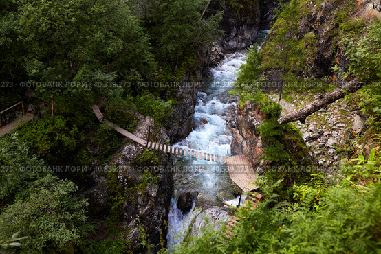 Suspension bridge over a mountain river. Beautiful summer landscape. Стоковое фото, фотограф Виктория Тельминова / Фотобанк Лори