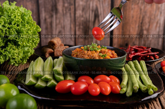 Sweet pork in a black bowl, complete with cucumbers, long beans, tomatoes, and side dishes. Selective focus. Стоковое фото, агентство Ingram Publishing / Фотобанк Лори
