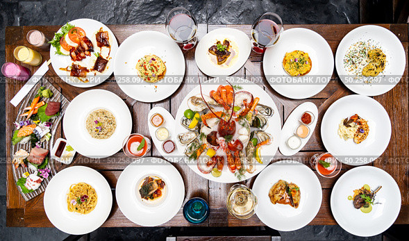 Table top view premium variety of international food in restaurant of lobster shrimp steak beef lamb pasta spaghetti risotto rice sushi sashimi and wine using for buffet food drink background. Стоковое фото, агентство Ingram Publishing / Фотобанк Лори