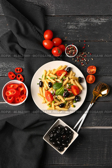 Тарелка с вкусным салатом из макарон и ингредиентами на темном деревянном фоне. Стоковое фото, фотограф Pixel_shot / Фотобанк Лори
