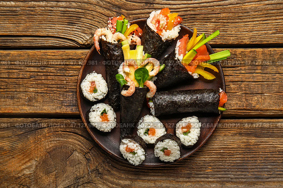 Тарелка с вкусными конусами и роллами суши на деревянном фоне. Стоковое фото, фотограф Pixel_shot / Фотобанк Лори
