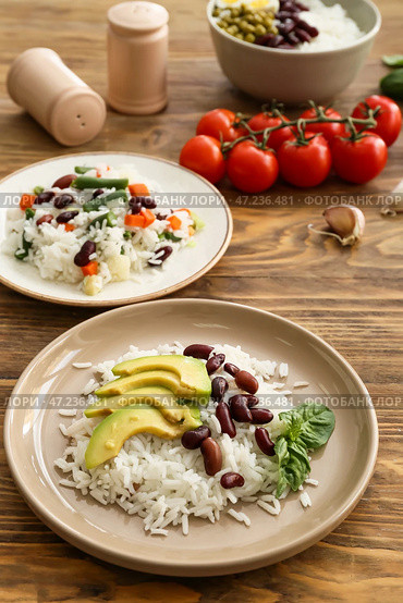 Тарелки со вкусным рисом, фасолью, овощами на столе. Стоковое фото, фотограф Pixel_shot / Фотобанк Лори