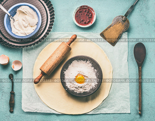 Tasty baking. Dough, rolling pin and bowl with flour and egg on light blue kitchen table background, top view. Стоковое фото, агентство Ingram Publishing / Фотобанк Лори