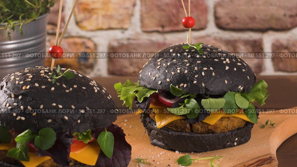 Tasty grilled veggie burger with lentils, dry tomato and thyme with black bread on wooden countertop. Стоковое фото, агентство Ingram Publishing / Фотобанк Лори