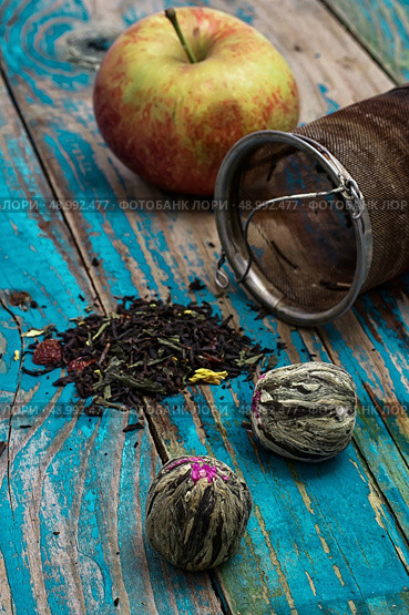 tea leaves and red apple on wooden background.The image is tinted in vintage style. tea leaves and red apple on wooden background. Стоковое фото, агентство Ingram Publishing / Фотобанк Лори