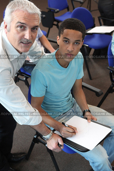 Teacher helping his student with his assignment. Стоковое фото, агентство Ingram Publishing / Фотобанк Лори
