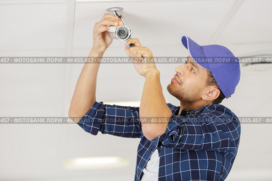 technician installing surveillance camera in the house carport. Стоковое фото, агентство Ingram Publishing / Фотобанк Лори