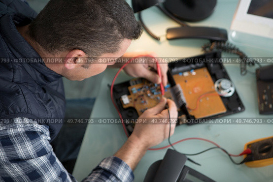 technician repairing a telephone handset. Стоковое фото, агентство Ingram Publishing / Фотобанк Лори