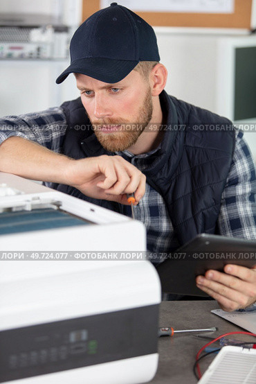 technician repairing printer and holding tablet. Стоковое фото, агентство Ingram Publishing / Фотобанк Лори