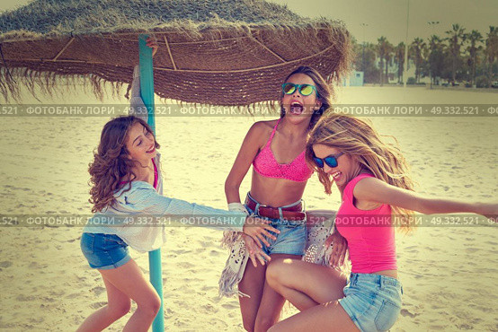 teen best friends girls under thatch umbrella having fun on a beach. Стоковое фото, агентство Ingram Publishing / Фотобанк Лори