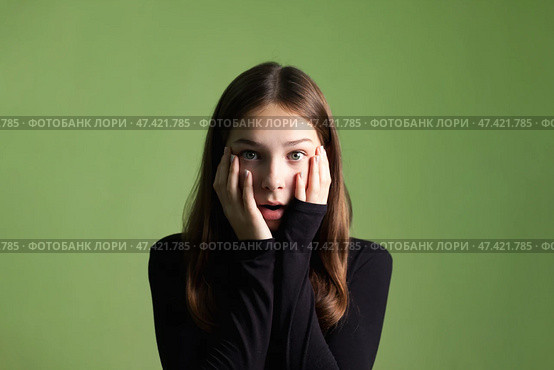 Teen Girl Expresses Surprise in a Studio With Green Background During a Creative Shoot. Стоковое фото, фотограф Aleksandr Golubev / Фотобанк Лори