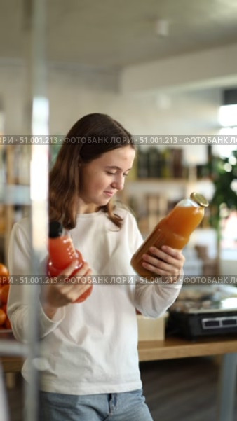 Teen girl hold packages bottles and choose consider juice in store. Стоковое видео, видеограф Яков Филимонов / Фотобанк Лори