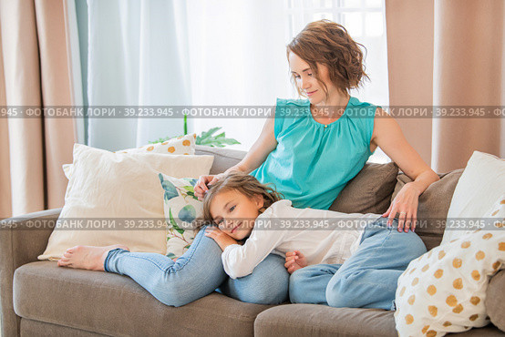 Teenage daughter is lying on the lap of a happy mother at home. Mom strokes the child on the head. Стоковое фото, фотограф Мария Мороз / Фотобанк Лори