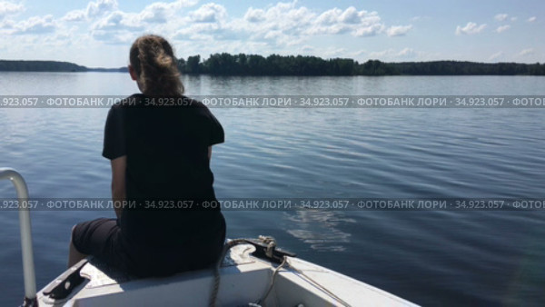 Teenager girl sits on bow of fast moving motorboat, speedboat floating on lake water surface, copyspace. Стоковое видео, видеограф Кекяляйнен Андрей / Фотобанк Лори