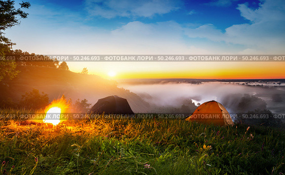 Tents and bonfire in steppe near river at sunrise. Стоковое фото, агентство Ingram Publishing / Фотобанк Лори