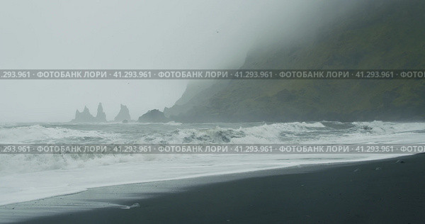 The black sand beach of Reynisfjara with waves hitting the shore on foggy rainy stormy day Vik, Icel. Стоковое фото, фотограф Igor Tichonow / Фотобанк Лори