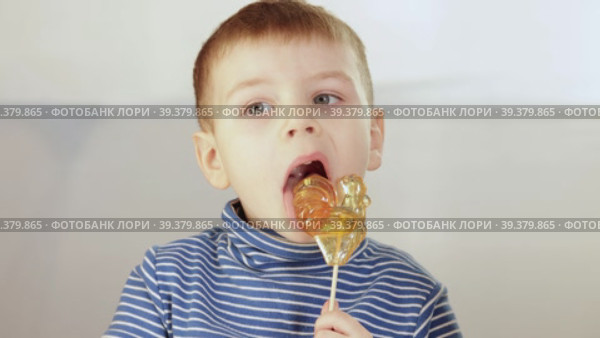 The boy eats a candy in the form of a cockerel. Стоковое видео, видеограф Потийко Сергей / Фотобанк Лори