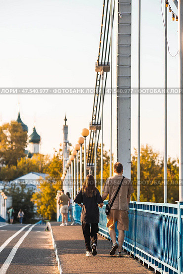 The bridge over the Kotorosl River to Damansky Island and people passing by. Yaroslavl, Russia. Редакционное фото, фотограф Photojuli / Фотобанк Лори