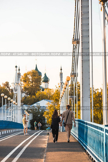 The bridge over the Kotorosl River to Damansky Island and people passing by. Yaroslavl, Russia. Редакционное фото, фотограф Photojuli / Фотобанк Лори