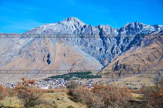 The Caucasus Mountains in Georgia and the village of Stepantsminda in the distance. The natural landscape. High peaks. The season is autumn. Стоковое фото, фотограф Наталия Кирсанова / Фотобанк Лори
