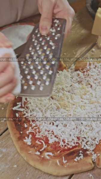 The chef expertly grates cheese on an almost finished pizza. Then the pizza is sent to the oven so that the cheese melts. Стоковое видео, видеограф Strunov David / Фотобанк Лори
