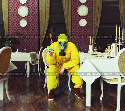 the man in a protective coverall sitting in an empty restaurant with a drink. Photo combination creative concept. Стоковое фото, агентство Ingram Publishing / Фотобанк Лори