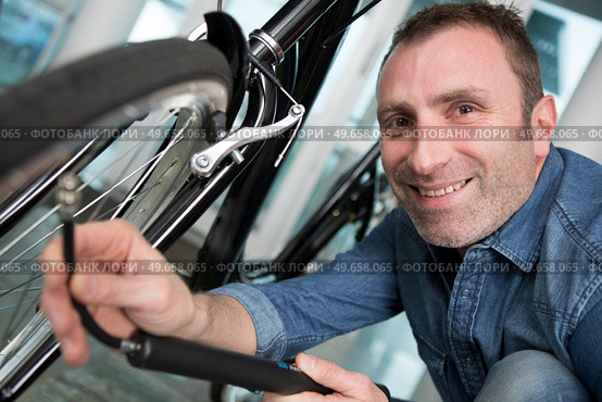 the man inflates bicycle wheel using a pump. Стоковое фото, агентство Ingram Publishing / Фотобанк Лори