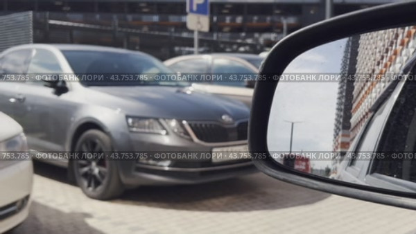 The movement of a car in the parking lot of a residential complex on a summer day. In the rear mirror, you can see high-rise apartments against the sky. Стоковое видео, видеограф Ярославский Максим / Фотобанк Лори