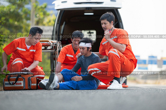 The paramedic  is assisting an injured man in an emergency situation on the road. Стоковое фото, агентство Ingram Publishing / Фотобанк Лори