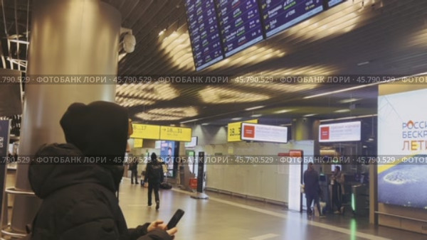The passenger checks the flight data on the smartphone at the departure board at the airport. Russia. Vnukovo. 12/25/24. Стоковое видео, видеограф Ярославский Максим / Фотобанк Лори