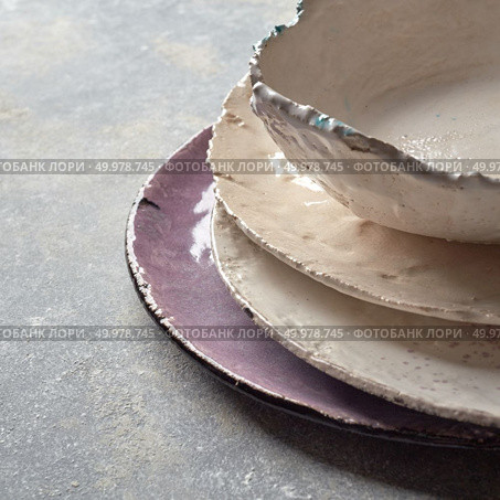The porcelain dishes handmade on a gray marble table with space under text. Traditional decorative ceramic handcrafted.. Decorative handcrafted pottery - bowls, plates covered with glazed on a gray background with place for text. . Стоковое фото, агентство Ingram Publishing / Фотобанк Лори