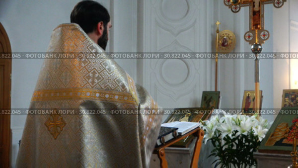 The priest in gold attire reads the bible in the church before the cross. Стоковое видео, видеограф Aleksandr Sulimov / Фотобанк Лори