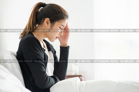 The sick woman had a headache and the hands touched her head on the bed. Стоковое фото, агентство Ingram Publishing / Фотобанк Лори