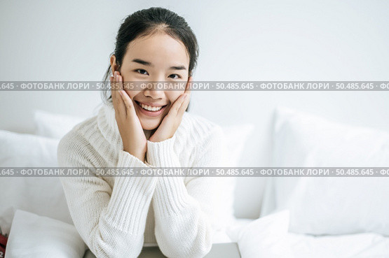 The woman sat on the bed, held the cheek, and smiled happily. Стоковое фото, агентство Ingram Publishing / Фотобанк Лори