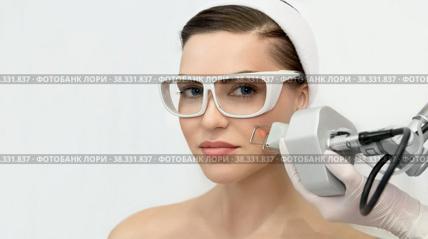 Therapist beautician makes a laser rejuvenation for the model by apparatus in a beauty salon. Стоковое фото, фотограф Юлия Тарасова / Фотобанк Лори
