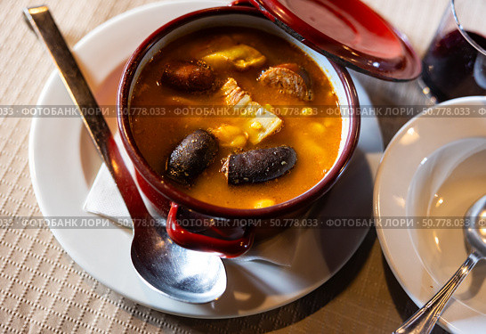 There is traditional Spanish dish on  table - Fabada Asturian in pot. Стоковое фото, фотограф Яков Филимонов / Фотобанк Лори