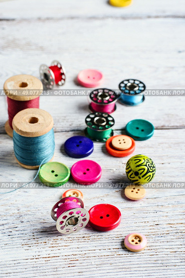 Threads and a set of buttons and bobbin on a bright light background. Working inventory seamstresses. Стоковое фото, агентство Ingram Publishing / Фотобанк Лори