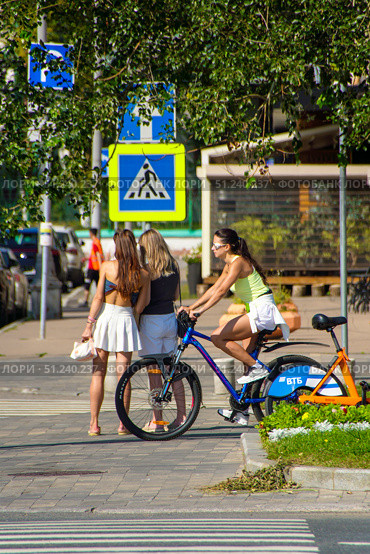 Three women are riding bicycles on a sidewalk.  Russia. Moscow. 24.08.25. Редакционное фото, фотограф Ярославский Максим / Фотобанк Лори