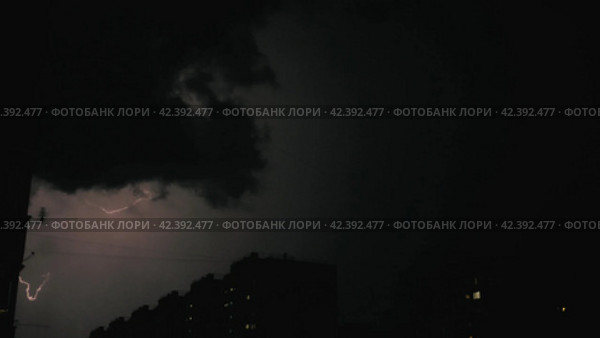 Thundercloud with lots of lightning in the night sky during a thunderstorm. Bright lightning flashes over the city and high-rise buildings. Concept of weather, disasters and storms. Стоковое видео, видеограф Воловодов Владимир / Фотобанк Лори