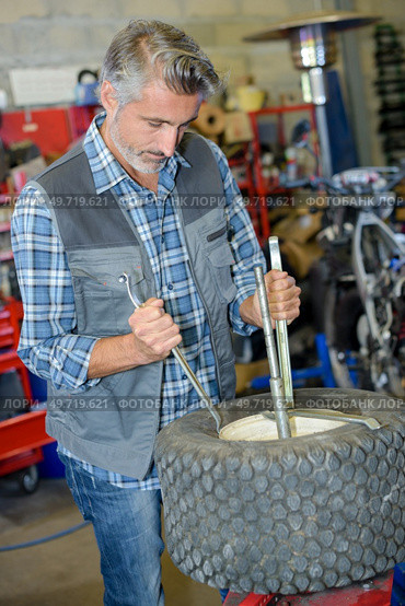 tire changer doing his work. Стоковое фото, агентство Ingram Publishing / Фотобанк Лори