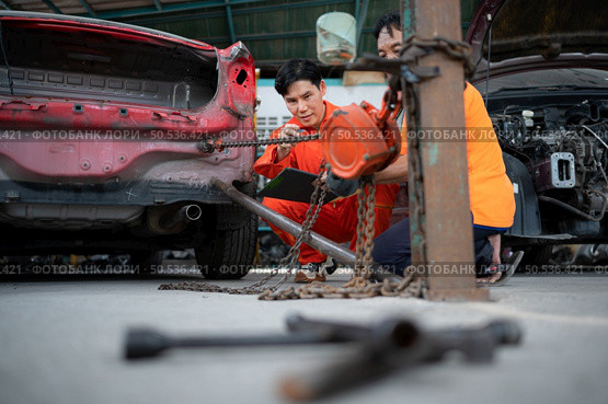 To return the automobile body to its former shape, an auto repair mechanic uses a machine to pull the car body caused by a heavy collision until it is deformed. Стоковое фото, агентство Ingram Publishing / Фотобанк Лори