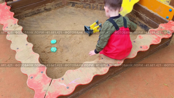 Toddler baby is playing in the sandbox on the playground. A child plays in the sand. Kid boy aged two years (two-year-old) Стоковое видео, видеограф Андрей Журавлев / Фотобанк Лори