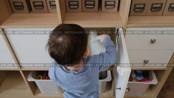 Toddler baby plays with household chemicals and detergent bottle from the closet. Child boy with cleaners products in home living room. Kid about two years old (age one year nine months) Стоковое видео, видеограф Андрей Журавлев / Фотобанк Лори